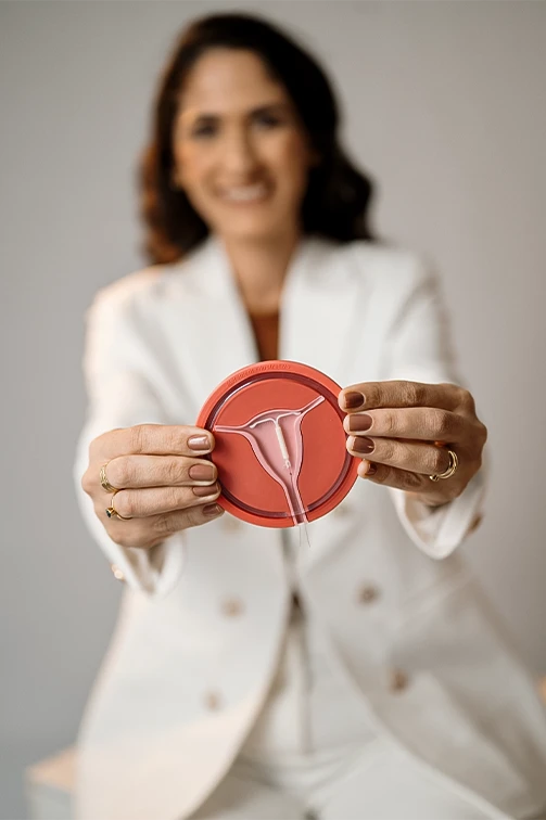 Dra. Melina Martins, ginecologista na Barra da Tijuca, mostrando um modelo de útero com DIU hormonal.